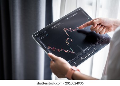 Hand holding digital tablet display stock market data with graph and chart for analyze and check before trading stocks online