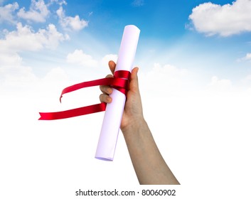 Hand Holding Diploma Wrapped With A Red Ribbon.