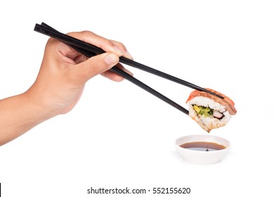 hand holding Dipping sushi roll in sauce isolated on white background