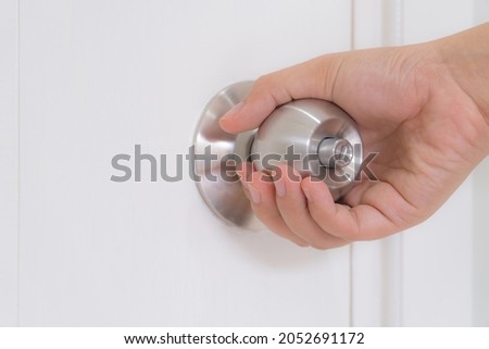 Hand holding door knob on white door. Opening door knob. copy space for text.