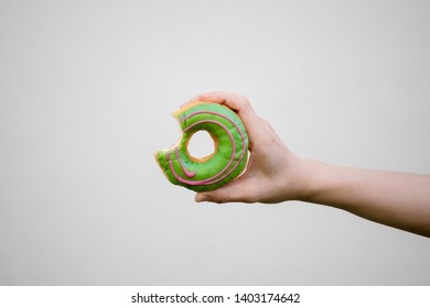 Hand Holding A Doughnut With A Bite Mark, On White Background.