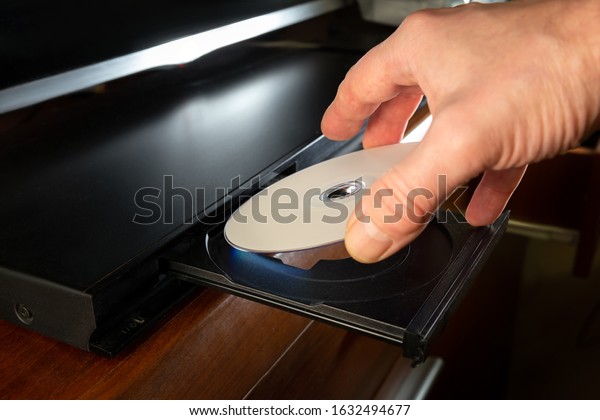 hand holding\
dvd-disk insert to dvd\
player