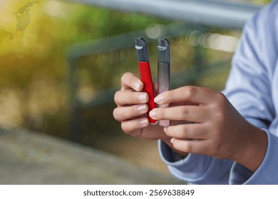 Mano sosteniendo un cigarrillo electrónico desde un piso de cemento, conceptos de tipos de cigarrillos, daños y peligros, sustancias adictivas.                                