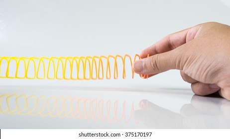 Hand Holding Elastic Spring Coil On Empty Background. Concept Of Business Flexibility. Slightly De-focused And Close-up Shot. Copy Space.