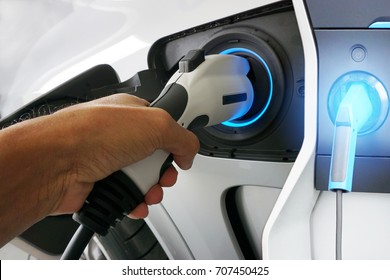 Hand holding Electric car charger. Power supply electric car charging for electric car technology transportation.                             