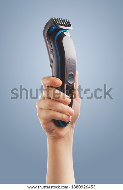 hand holding an electric hair clipper on a\
blue background