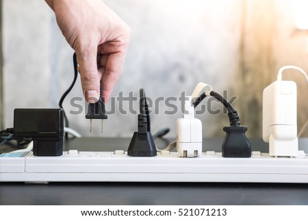 Hand holding electric plug, Multiple socket with connected plugs.