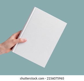 Hand holding empty book mock up over minimal background. High quality photo