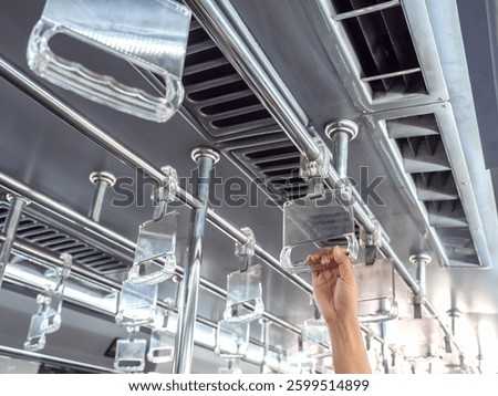 Hand holding empty clear plastic frame, bus handle, hanging straps, grab handle bar in airport shuttle bus. Blank space for advertisement on city subway handrail bus, standing hand holder.