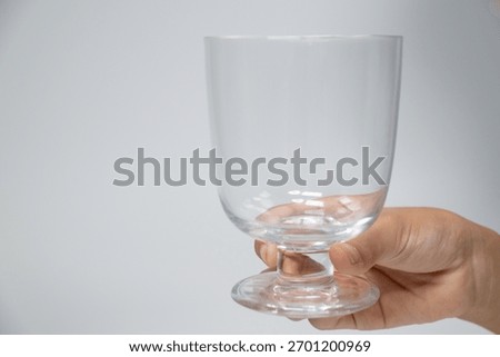 Hand holding an empty clear stemmed glass