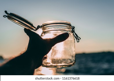 Hand Holding Empty Jar In The Sunlight