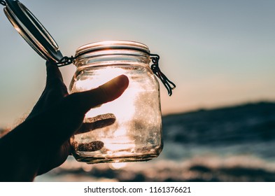 Hand Holding Empty Jar In The Sunlight