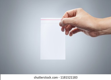 Hand Holding Empty Plastic Ziplock Bag On Grey Background