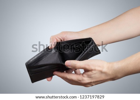 Hand holding an empty purse on grey background