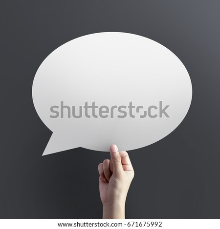 Hand holding empty speech bubble on dark background