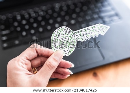 hand holding encryption key icon made of circuits and LED lights in front of laptop keyboard, concept of digital security or data encryption