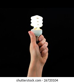 Hand holding energy efficient white light bulb on black background