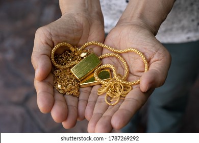 Hand Holding Expensive Gold Jewelry, Gold Bar, Gold Necklace.