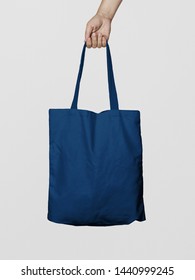 Hand Holding Fabric Canvas Tote Bag or Goodie Bag Isolated on Blue Navy Colour Background - Shutterstock ID 1440999245