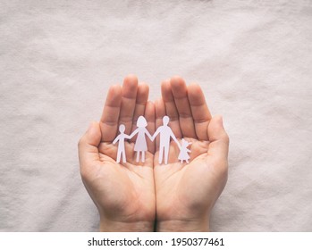 Hand holding family paper cut on fabric background. Family day concept, foster care, domestic violence, homeschool, international day of families, world mental health day, world autism awareness day.