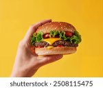 Hand holding a fast food cheeseburger