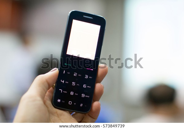 a hand holding a feature\
phone