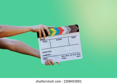 Hand Holding Film Slate Colors Board For Movie Cinema And Television Industry On Green Background