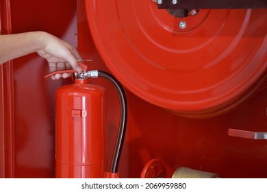 Hand Holding Fire Extinguisher, Fire Extinguisher And Fire Hose Reel Station Available In The Office