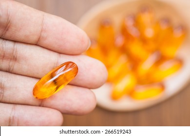 Hand Holding A Fish Oil Capsule With Blurred Background