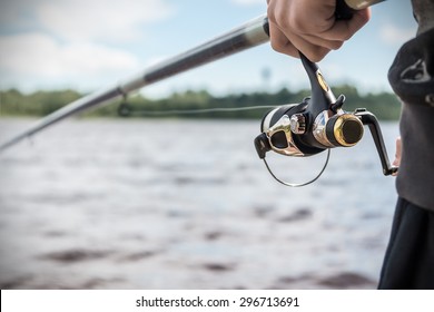 hand holding a fishing rod with reel. Focus on Fishing Reels 