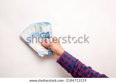 Hand holding five hundred mexican pesos bills as a payment on a white background