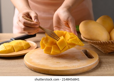 Hand holding fork and eating Thai mango fruit (Nam Dok Mai), Tropical fruit in summer season - Powered by Shutterstock