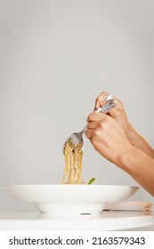 Hand Holding Fork And Spoon Eating Spaghetti Truffle Cream Sauce.