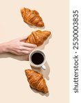 Hand holding fresh croissant on yellow background with shadow and cup of espresso coffee. Design concept for breakfast pastry mockup or banner. Top view and copy space.