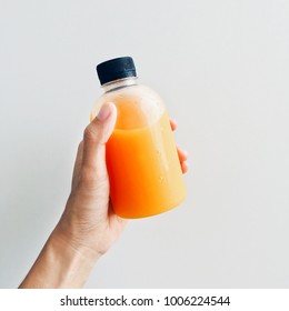 Hand Holding Fresh And Healthy Orange Juice In A Bottle Isolated On A White Background