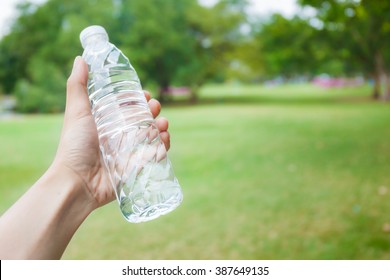 Hand holding fresh water bottle in the park 