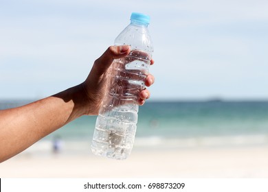 Hand Holding Fresh Water Bottle In The Sea