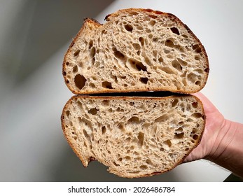 A hand holding a freshly cut loaf of delicious sourdough bread - Powered by Shutterstock