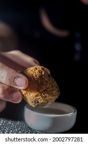 hand holding a fried dumpling with a small pot of mayonnaise,copy space and man in the background. - Shutterstock ID 2002797281