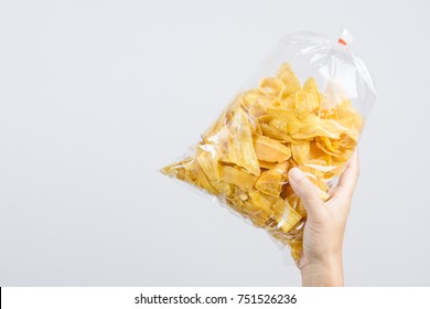 Hand Holding Fried Sliced Banana Chip In Food Plastic Bag Tied By Rubber On White Background