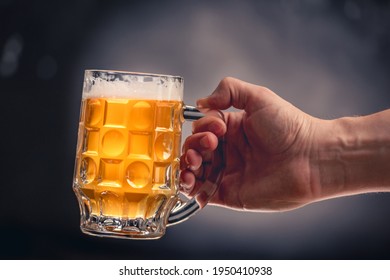 Hand holding full beer mug isolated on dark grey background