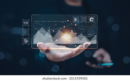 Hand holding a futuristic digital interface with data visualization and business analytics in a dark background. - Powered by Shutterstock