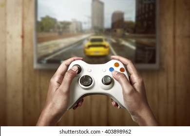 Hand Holding Game Console Controller Playing Racing Game On The Television