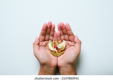 Hand holding Garuda Pancasila emblem Isolated on white background. Indonesia independence day 17th August, pancasila day concept. - Shutterstock ID 2147800941