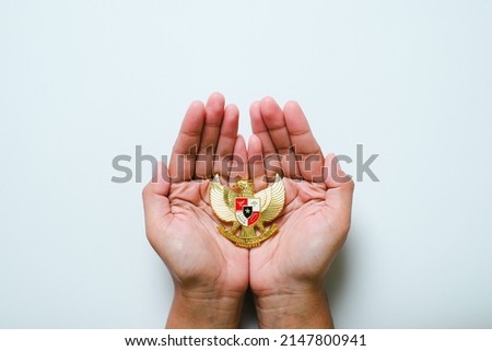 Hand holding Garuda Pancasila emblem Isolated on white background. Indonesia independence day 17th August, pancasila day concept.