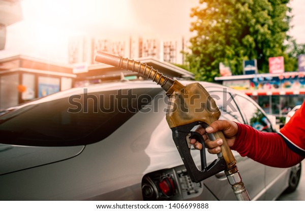 Hand\
holding gas nozzle in gas station for car\
refueling