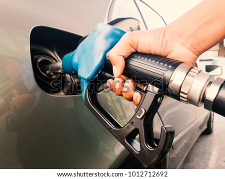 Hand holding gasoline nozzle for car refueling at gas station