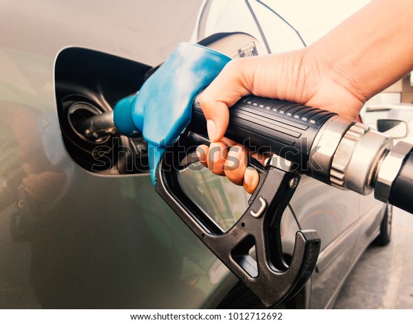 Hand holding gasoline nozzle for car refueling at\
gas station