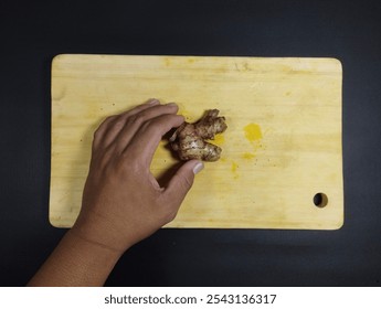 hand holding ginger with a wooden board background - Powered by Shutterstock