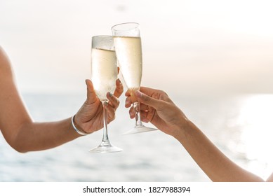 Hand holding a glass drinking wine on Sunset sea background.